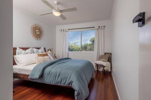 Schlafzimmer mit einem Bett, einem Deckenventilator und einem Fenster in der Unterkunft The Sunshine Shack - Boutique Holiday Home in Sunshine Beach