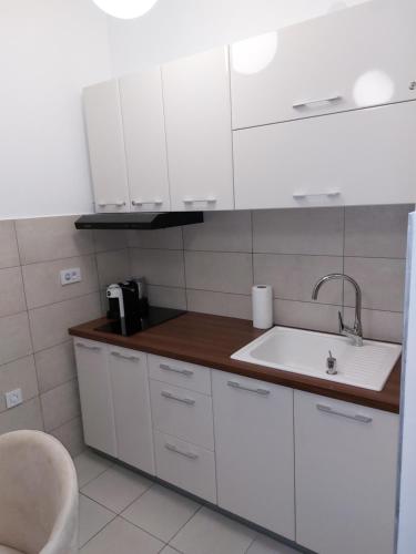 uma cozinha com armários brancos e um lavatório em JAGODINA apartman em Jagodina