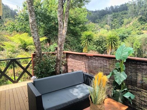 a black couch sitting on a wooden deck with trees at Riverside Accommodation in Karangahake