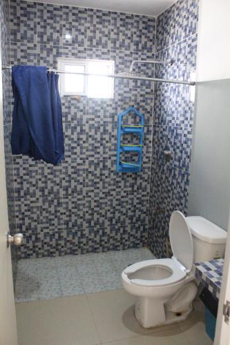 a bathroom with a toilet and a shower with blue towels at Casa Rojas, a una calle de la playa! in Progreso