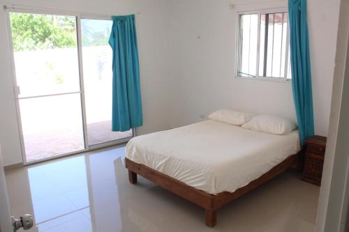 a bedroom with a bed with blue curtains at Casa Rojas, a una calle de la playa! in Progreso