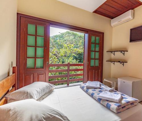 a bedroom with a bed and a large window at Pousada do Marquinhos in Trindade