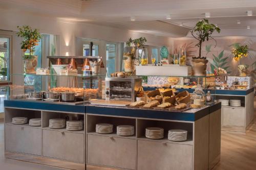 a restaurant with a counter with plates and food at NH Catania Parco degli Aragonesi in Catania