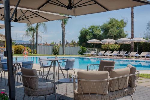a pool with tables and chairs next to a swimming pool at NH Catania Parco degli Aragonesi in Catania