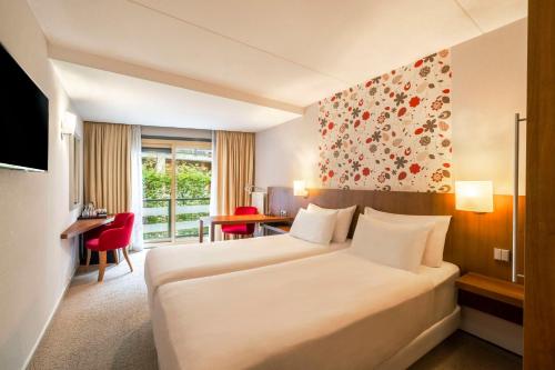 ein Hotelzimmer mit einem großen Bett und einem Schreibtisch in der Unterkunft Fletcher Hotel-Restaurant Sparrenhorst-Veluwe in Nunspeet