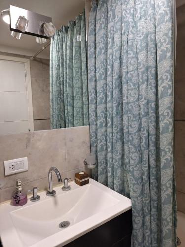 un bagno con un lavandino e una tenda da doccia di Edificio Juana del Mar a Mar del Plata