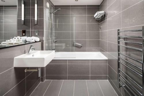 a bathroom with a sink and a bath tub at Radisson Blu Hotel, Cardiff in Cardiff