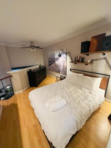 a bedroom with a large white bed with a wooden floor at HiFi Sound & Comfort - Uptown Dallas / 2-story loft in Dallas
