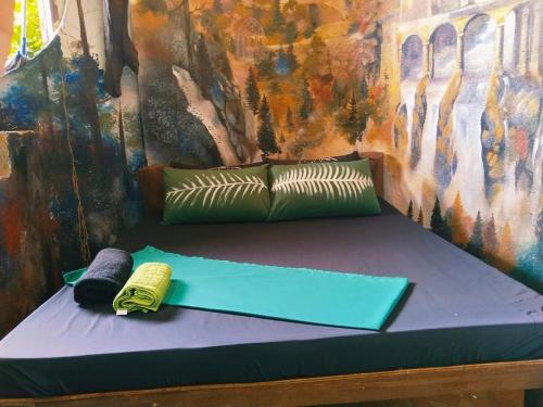 a bed with two pillows and a painting on the wall at Sanctuaria Treehouses Busuanga in Busuanga