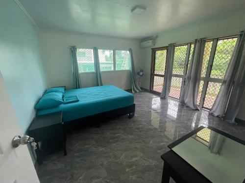 1 dormitorio con 1 cama con sábanas azules y ventanas en Aunty Fou's Home - Vaivase, en Apia