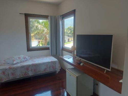 a bedroom with a bed and a flat screen tv at Casarão Caborê in Paraty