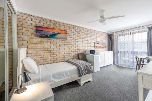 ein Schlafzimmer mit Ziegelwand und ein Bett in einem Zimmer in der Unterkunft Coast Inn Motel in Ballina