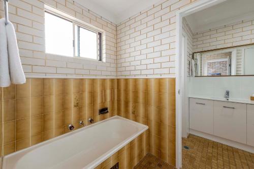 La salle de bains est pourvue d'une baignoire, d'un lavabo et d'une fenêtre. dans l'établissement Coast Inn Motel, à Ballina