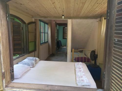 um quarto com uma cama dentro de uma casa em Hostel e Camping Rio das Pedras em Camburi