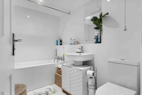 a white bathroom with a sink and a bath tub at Little Venice Garden Apartment in London