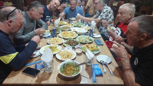 een groep mensen die rond een tafel eten bij Green Bamboo Lodge Resort in Cat Tien