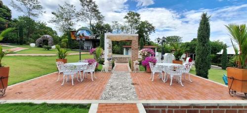 a patio with white tables and chairs in a garden at NG Glamping a 20 min de Neiva in Neiva