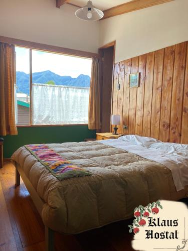 sypialnia z dużym łóżkiem i dużym oknem w obiekcie Hostal Klaus w mieście Pucón
