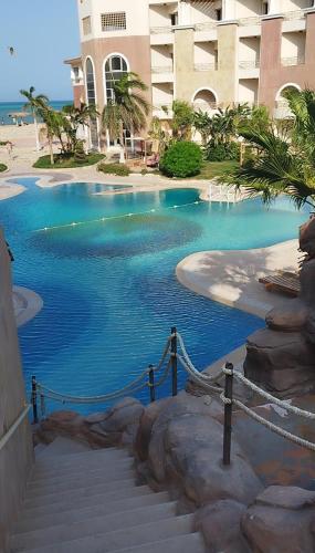 a swimming pool with stairs in front of a building at royal beach resort hurghada in Hurghada
