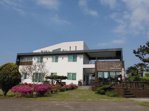 a large white building with flowers in front of it at Moon Forest Guesthouse in Jeju