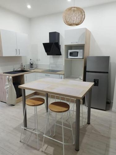 RomagnatにあるJoli appartement en Auvergneのキッチン(木製テーブル、スツール2脚付)