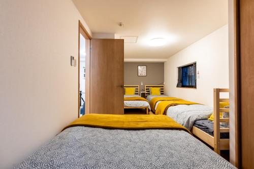 fila de camas en una habitación con camas amarillas en Furinkyo・楓林居 7号館, en Osaka