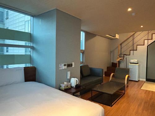 a bedroom with a bed and a chair and a staircase at Elysia Boutique Hotel in Busan