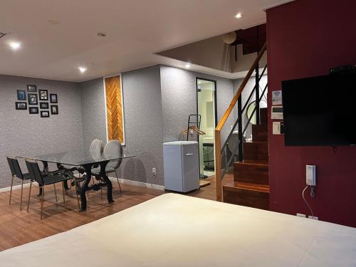 a living room with a dining table and a tv at Elysia Boutique Hotel in Busan