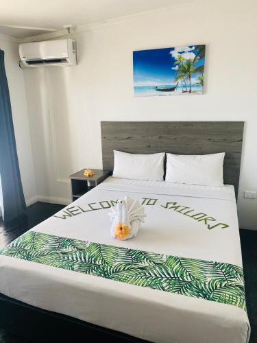 a bedroom with a large white bed with a flower on it at Sailors Beach Fiji in Nadi