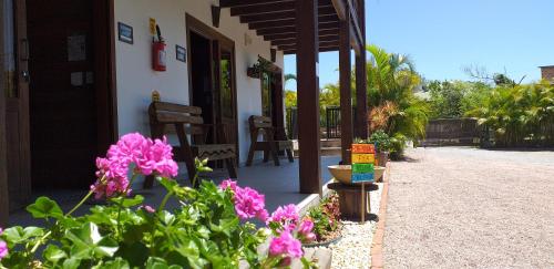 a porch of a house with some pink flowers at Pousada Gauleses in Praia do Rosa