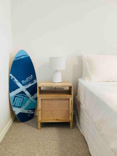a blue surfboard leaning against a wall next to a bed at Seabreeze Luxury Apartment Kiama in Kiama