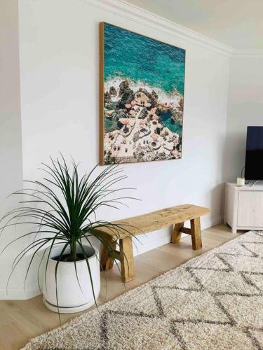 a living room with a bench and a potted plant at Seabreeze Luxury Apartment Kiama in Kiama