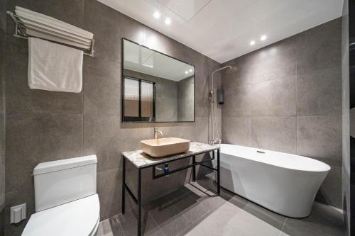 ein Badezimmer mit einem Waschbecken, einer Badewanne und einem WC in der Unterkunft Jecheon The Wall Hotel in Jecheon