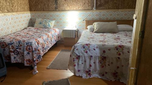 a small bedroom with two beds and a lamp at Mecohue in Chaitén