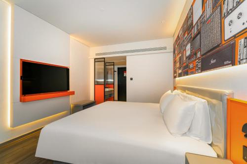 a bedroom with a white bed and a flat screen tv at Ibis Styles Hotel - 260M from Guangji Street Subway Station in Xi'an