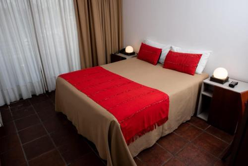 a bedroom with a large bed with red pillows at Hotel boutique Tramas Andinas in Salta