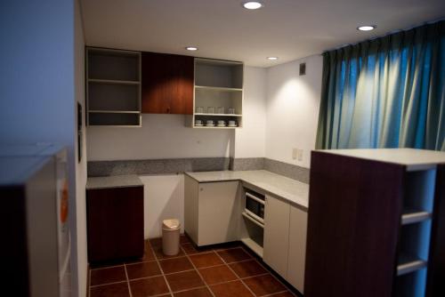 a small kitchen with white cabinets and a blue curtain at Hotel boutique Tramas Andinas in Salta