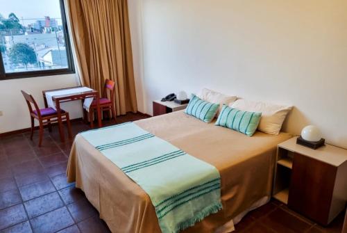 a bedroom with a bed and a table and a window at Hotel boutique Tramas Andinas in Salta