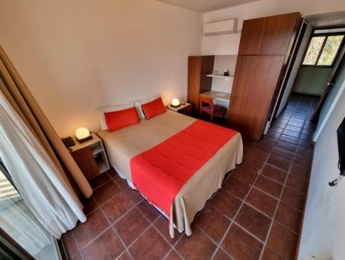 a bedroom with a bed with red sheets and a desk at Hotel boutique Tramas Andinas in Salta