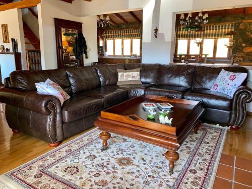 a brown leather couch with a coffee table in a living room at πετρινο σαλε in Palaios Agios Athanasios
