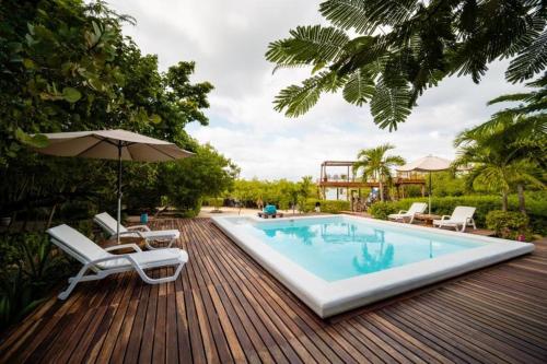 a pool with chairs and an umbrella on a wooden deck at Hotel Playa Scondida in Barú