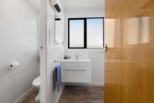baño blanco con lavabo y ventana en ASURE Oakleigh Motel, en Gore