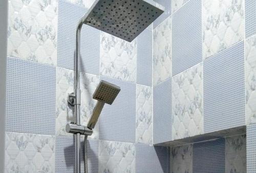 La salle de bains est pourvue d'une pomme de douche et de carrelage bleu et blanc. dans l'établissement RedDoorz @ Vine Molave, à Molave
