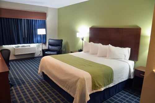 una habitación de hotel con una cama grande y una silla en Brookstone Lodge & Suites - Emmetsburg en Emmetsburg