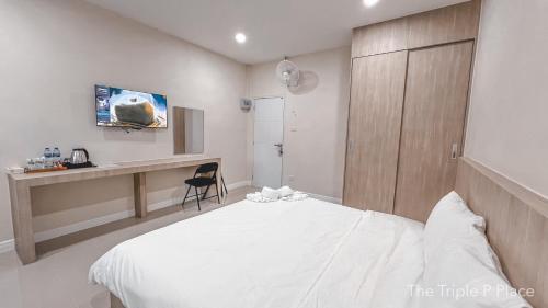 um quarto com uma cama branca e uma secretária em The Triple P Place เดอะ​ทริปเปิลพีเพลส em Ban Non Sung