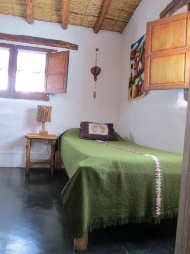 a bedroom with a green bed and a window at La Calabaza Cabaña in Tilcara