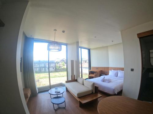 a bedroom with a bed and a couch and a window at The Fields Hotel and Apartment in Seminyak