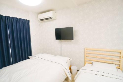 um quarto com duas camas e uma televisão na parede em Direct to Namba,Korean town102 em Osaka