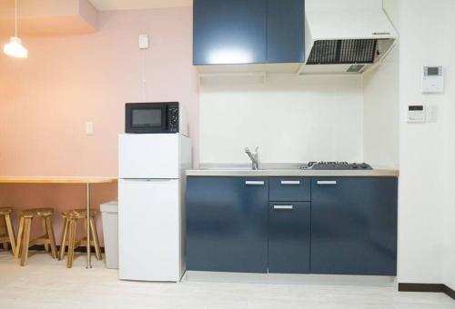 uma cozinha com um frigorífico e uma mesa com um micro-ondas em Direct to Namba,Korean town102 em Osaka