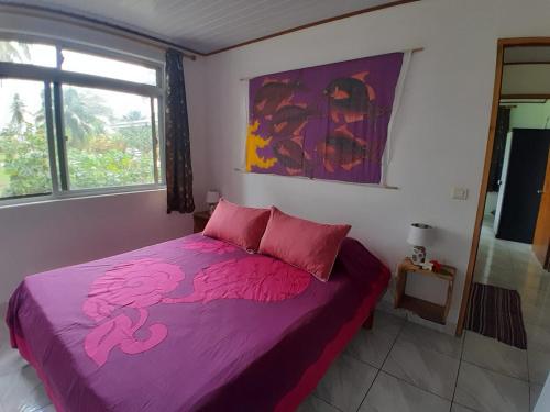 een slaapkamer met een bed met roze lakens en een raam bij CHEZ VAIANA in Parea
